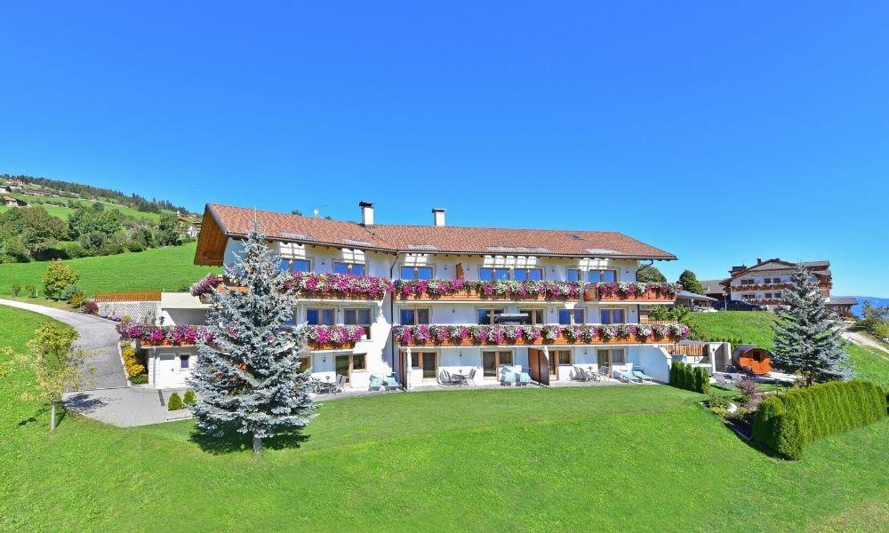 Панорамный вид на альпийскую резиденцию среди зеленых лугов и горных вершин